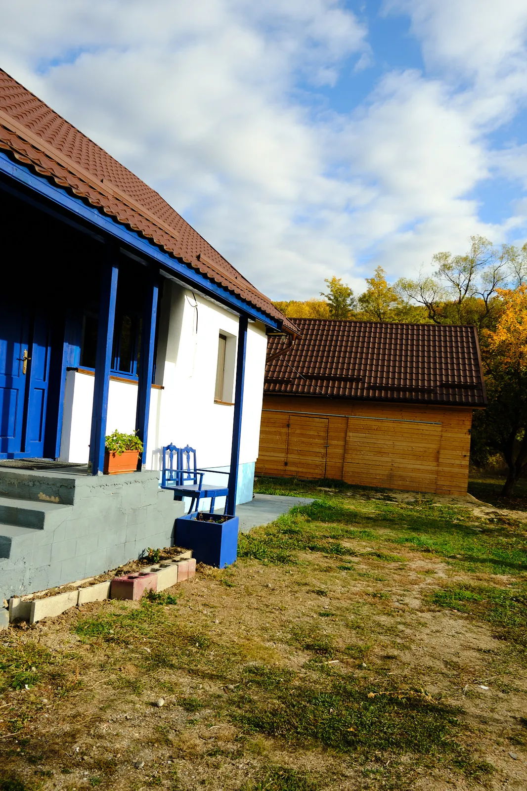 Casa Bunicilor: prispa albastră, casa albă și șura de lemn, toamna